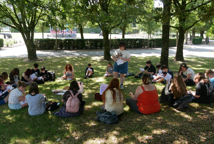 Culture Club members sitting together beneath the trees during an outdoor summer camp activity in People’s Park, Waterford.