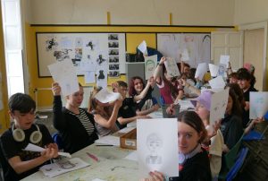 Young people showing their drawings during a Culture Club summer camp art activity at Little Red Kettle.